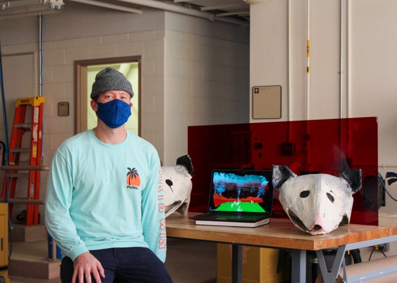 Craeative technologies masters student Eric Schoenborn sits in front of his animatronic project.