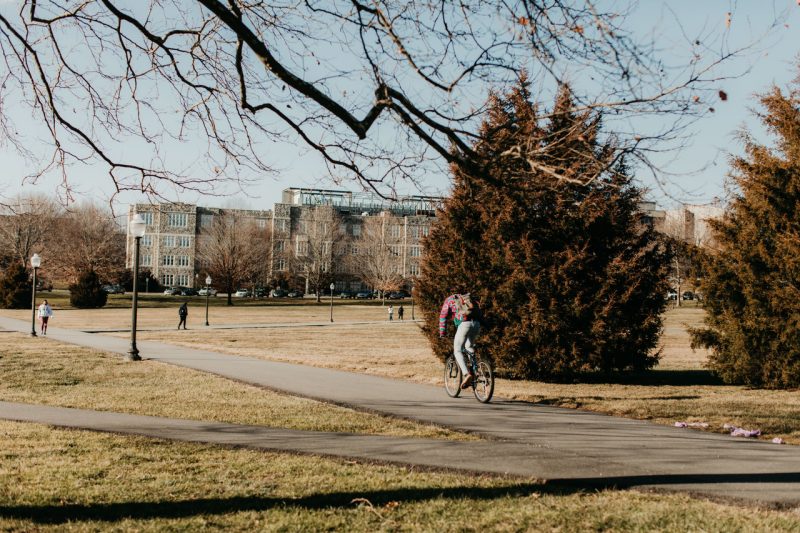 A student rides a bike across the Drillfield 