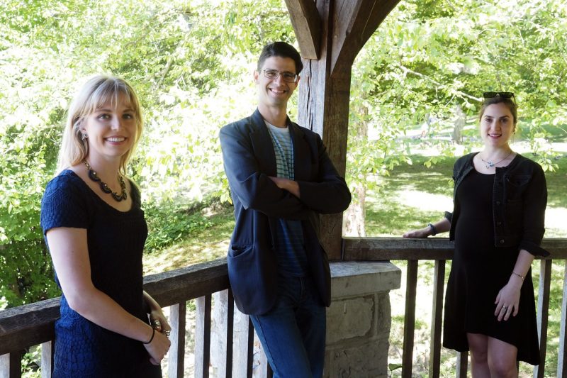 Group photo of the three guest editors standing in a gazebo surrounded by greenery.