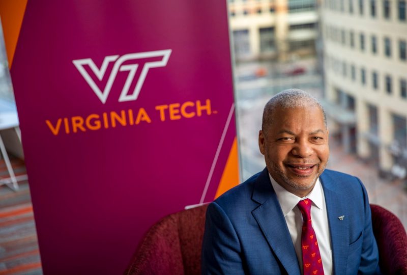 Lance Collins sitting in front of the Virginia Tech logo