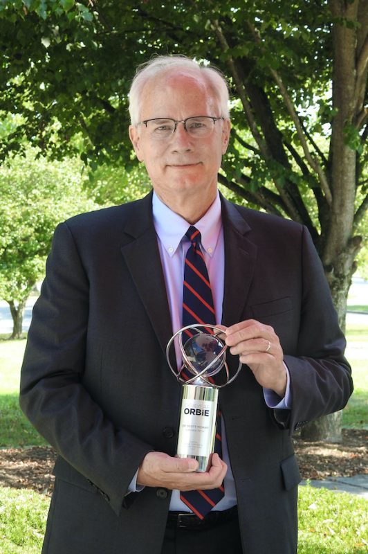 Scott Midkiff holding brass and crystal ORBIE award