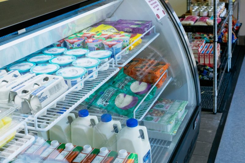 A view inside a refrigerated display case at The Market of Virginia Tech containing milk, eggs, cheese, yogurt, and tofu.