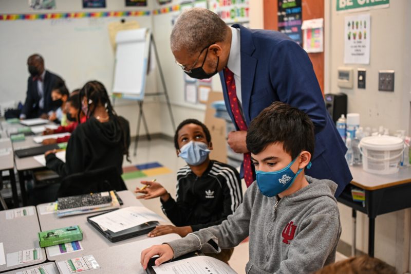 Student in floral mask holds micro:bit device in classroom