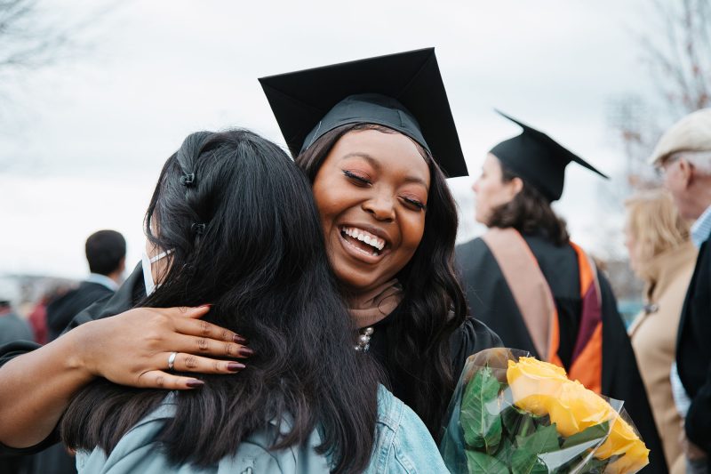 A graduate hugs someone outside the fall 2021 graduate commencement ceremony