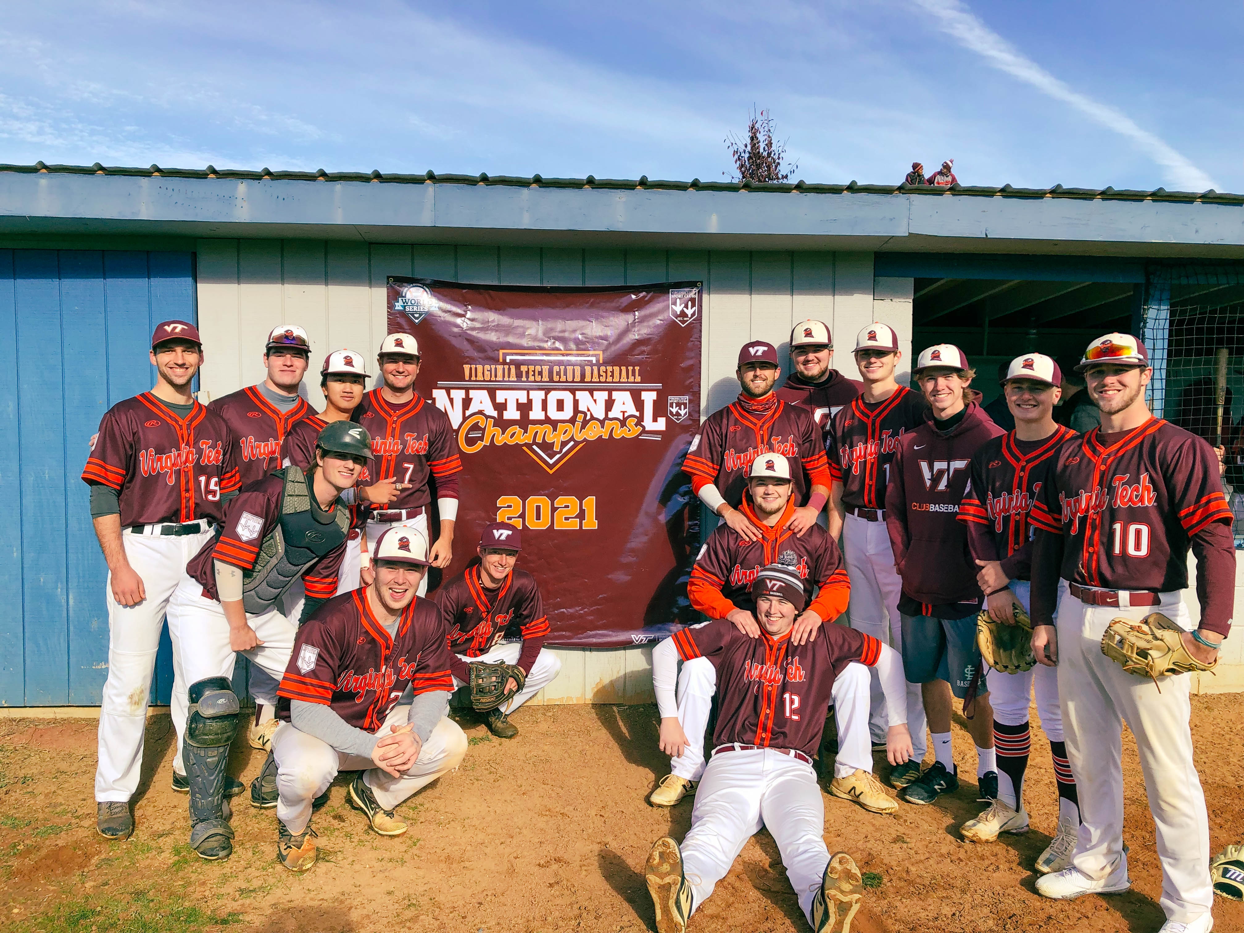 The Virginia Tech Club Baseball team stands together on the baseball field, posing with their national champions trophy.