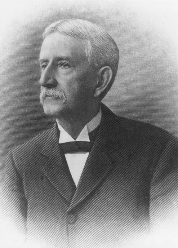A historic photograph of John McLaren McBryde wearing a dark suit and white high colored shirt.