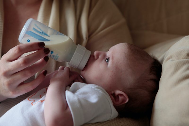A baby is fed formula fromt a bottle.