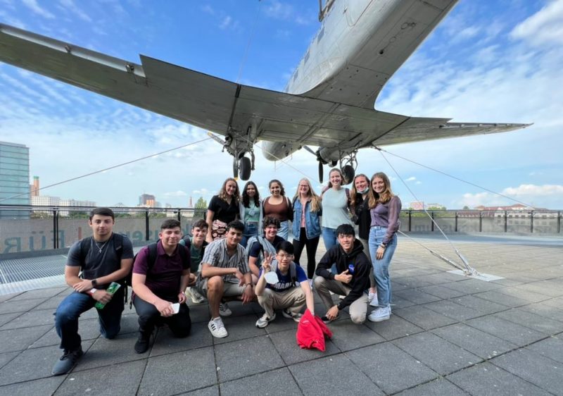 Students stand underneath an airplane at the German Technology Museum.