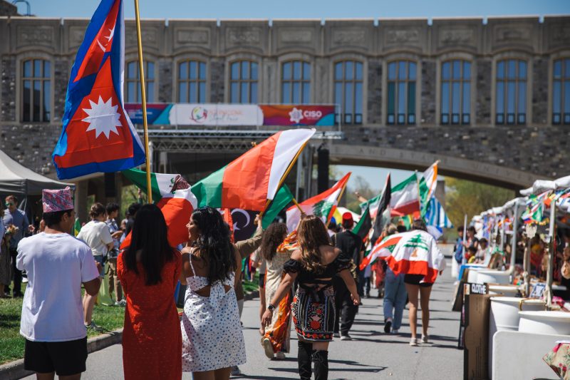People holding international flags parade in front of Torgersen Bridge