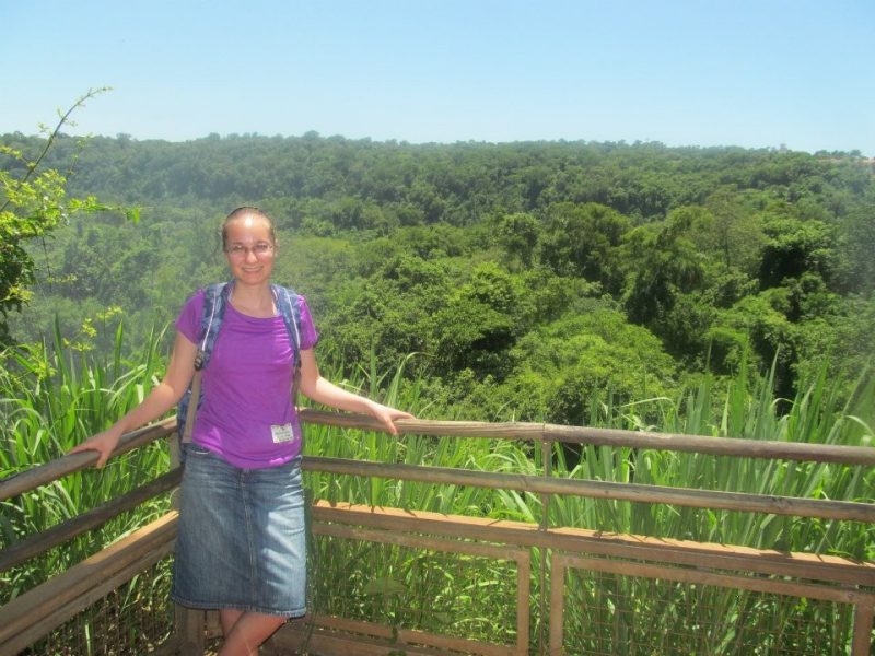 Rebekah Slabach, in a purple shirt, stands in front of a lush backdrop of jungle greenery in Costa Rica.