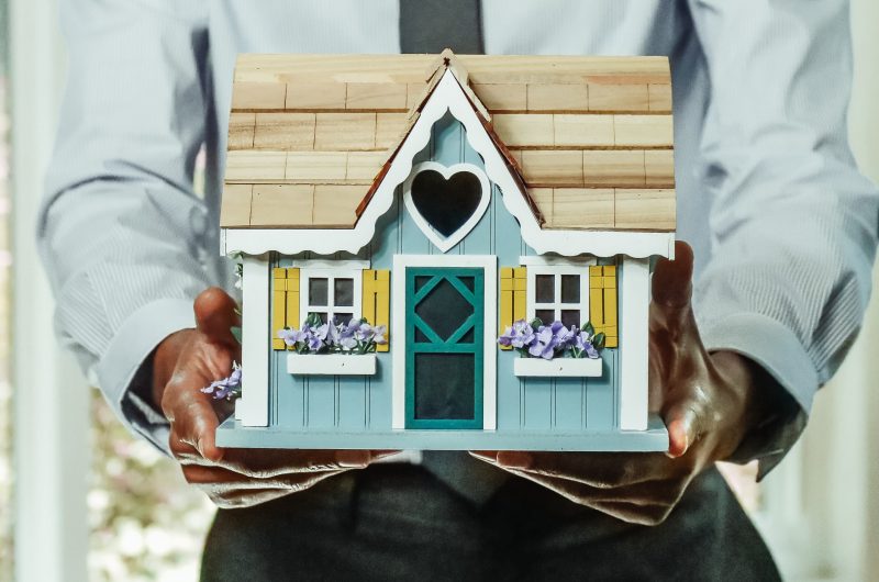 A real estate agent holding a model house. Photo courtesy Pexels