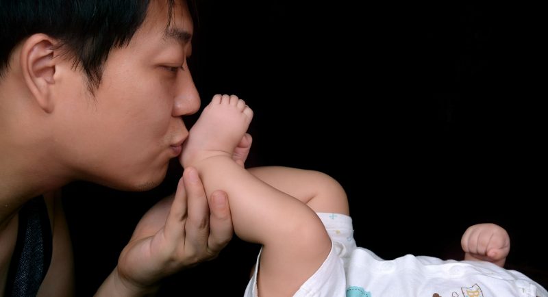 Close-up photo of a father kissing his baby's foot
