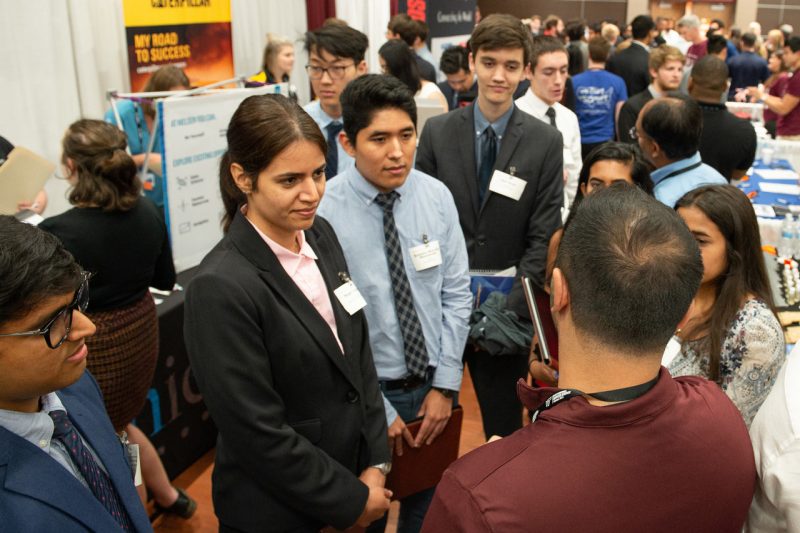 Students talking with a recruiter at a career fair.